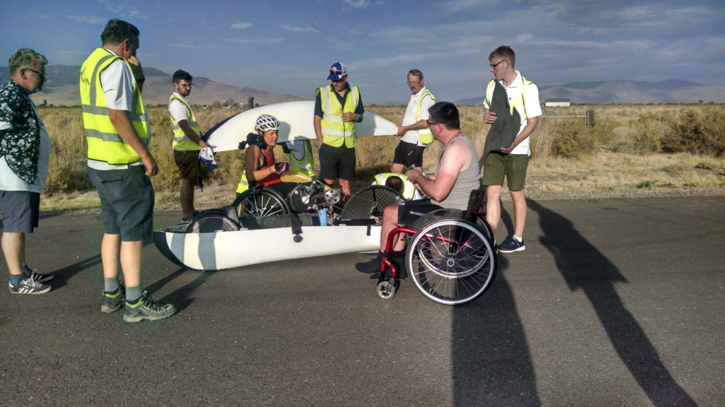 Two handcyclists sitting next to handcycle